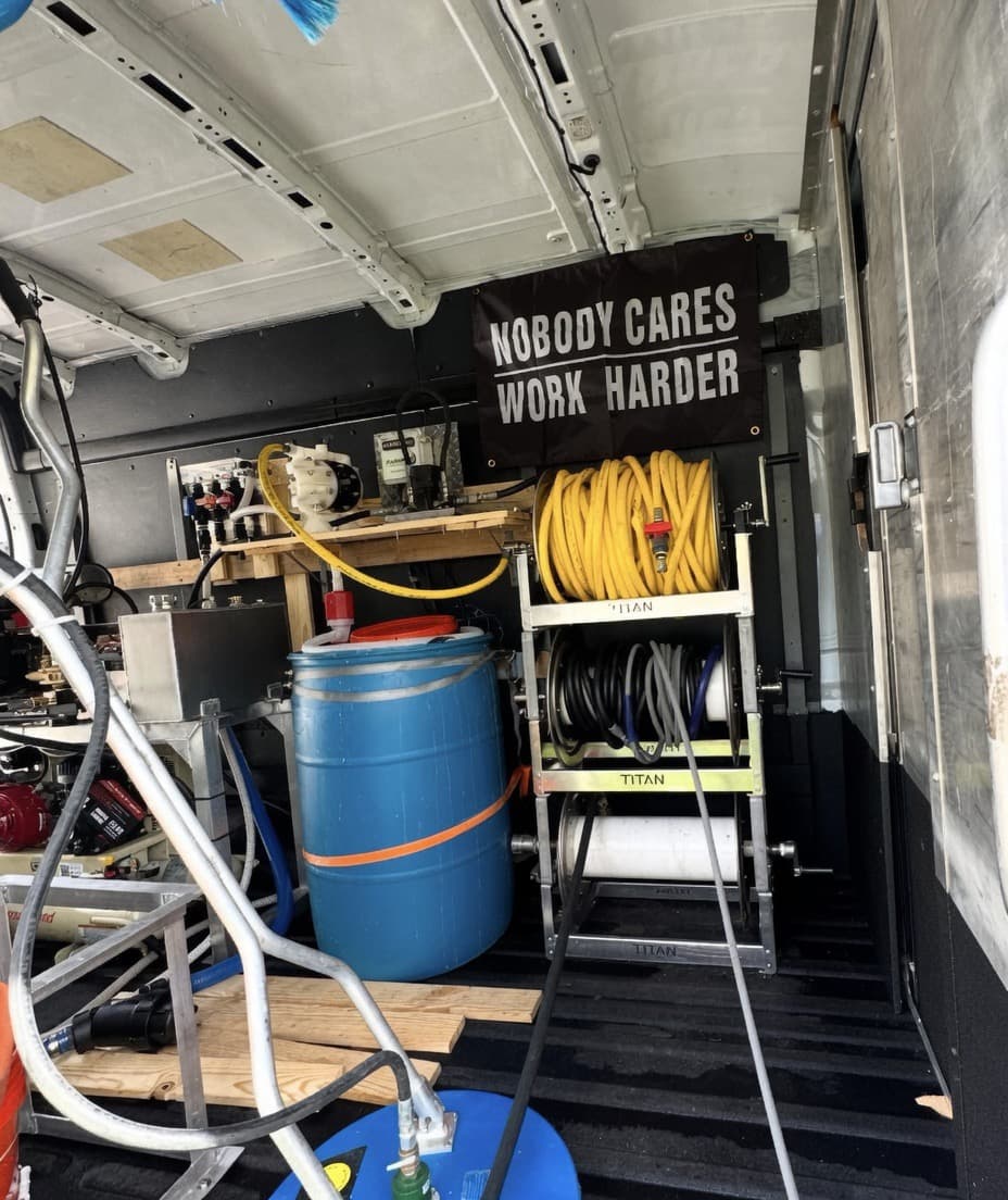Inside the Triton van showing professional soft wash tanks, pumps, and hose reels